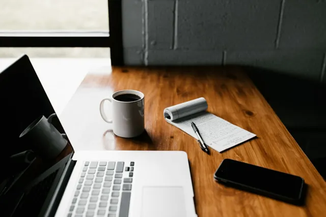 A notebook and laptop on a writing desk; editorial photograph